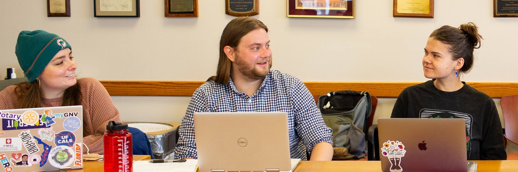 A young man confers with two women sitting on either side in a classroom at the Ostrom Workshop.